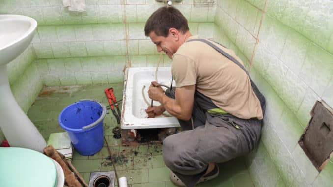 Handwerker reinigt verstopften Duschabfluss Handwerker reinigt verstopften Duschabfluss